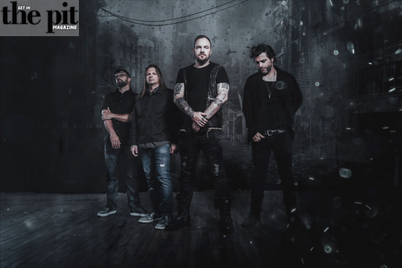 Four male band members of Saint Asonia standing together in a dimly lit urban setting with floating particles around them, with "the pit magazine" logo in the top left corner.
