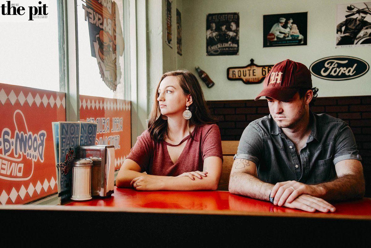 Two people sitting at a Ragland diner counter, looking in opposite directions, with vintage decor in the background.