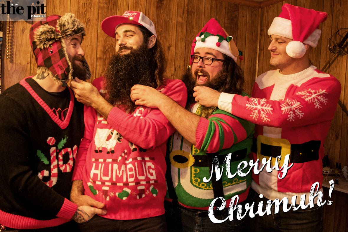 Four men in festive sweaters and santa hats laughing and enjoying a holiday gathering, with one man playfully tugging another's beard. A "Merry Chrismuh from Voltagehawk!" text is