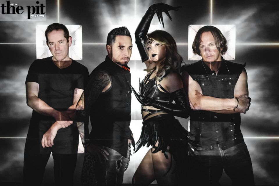 Four band members from Reality Suite posing dramatically against a backdrop with radiant light beams, featuring distinctive rock attire.