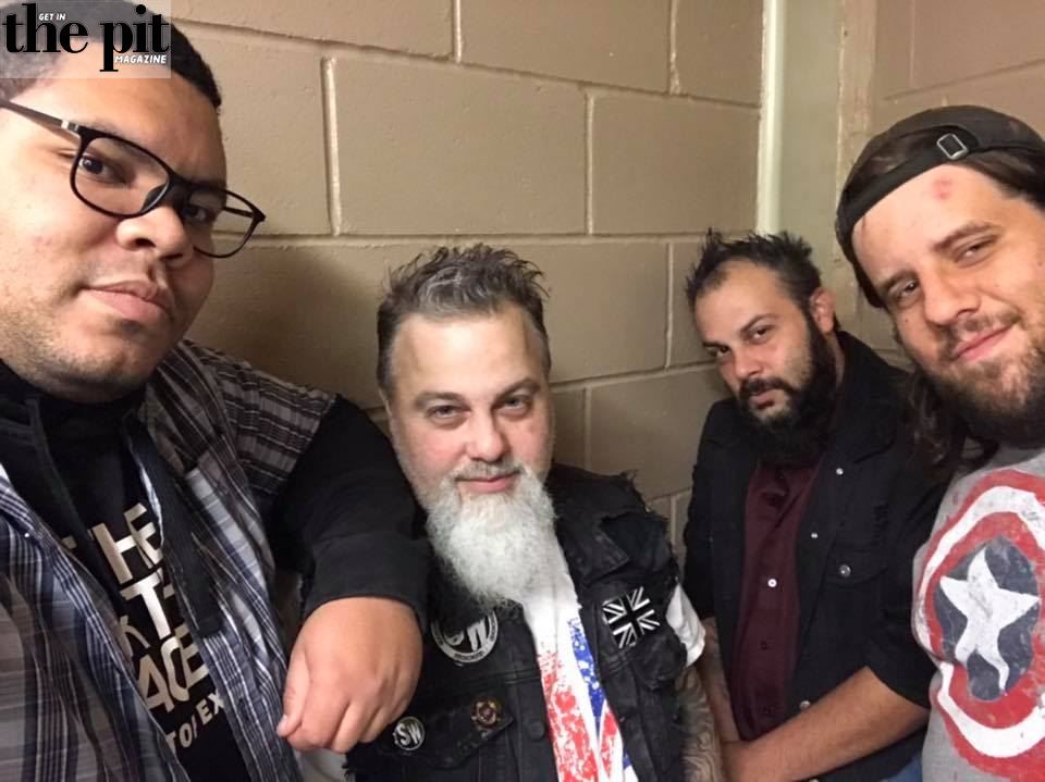 Four men posing for a selfie in a Springwood hallway, featuring a variety of styles including beards and casual attire.