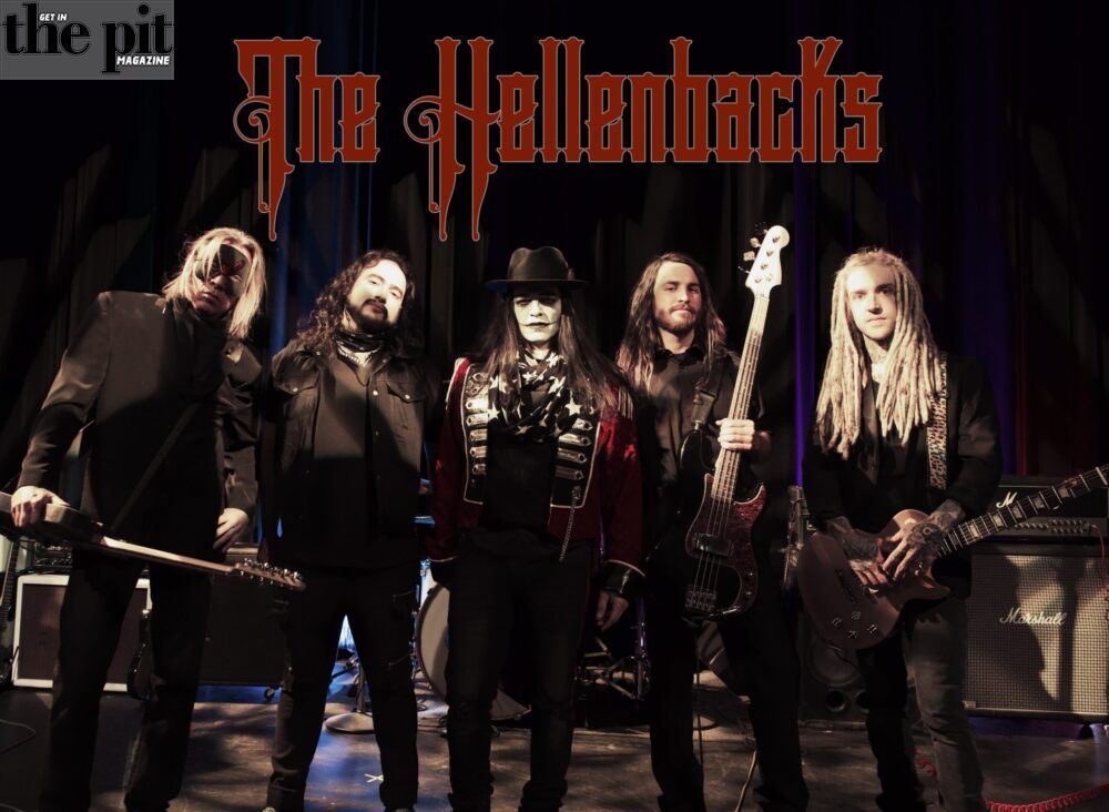 Five members of the band The Hellenbacks posing with their instruments on stage under the band's logo.