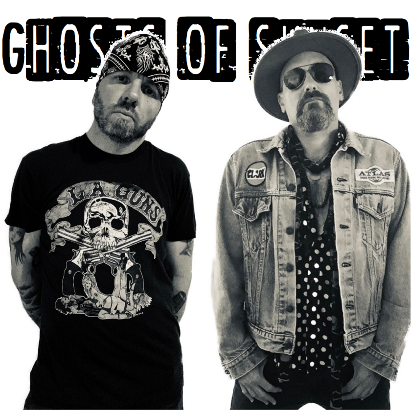Two men posing for a promotional photo for their band, "Ghosts of Sunset," with one wearing a skull graphic t-shirt and the other in a denim vest.
