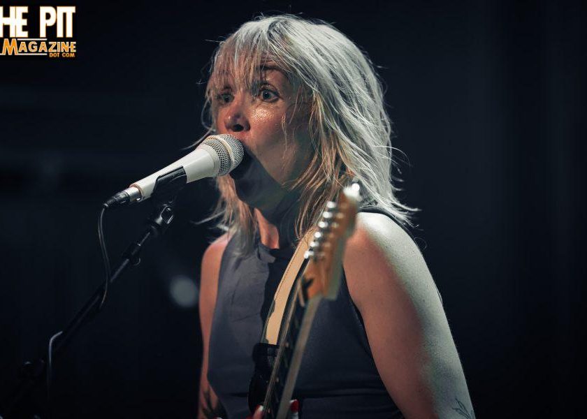Four men posing for a band photo with 'Get in the Pit Magazine' text.